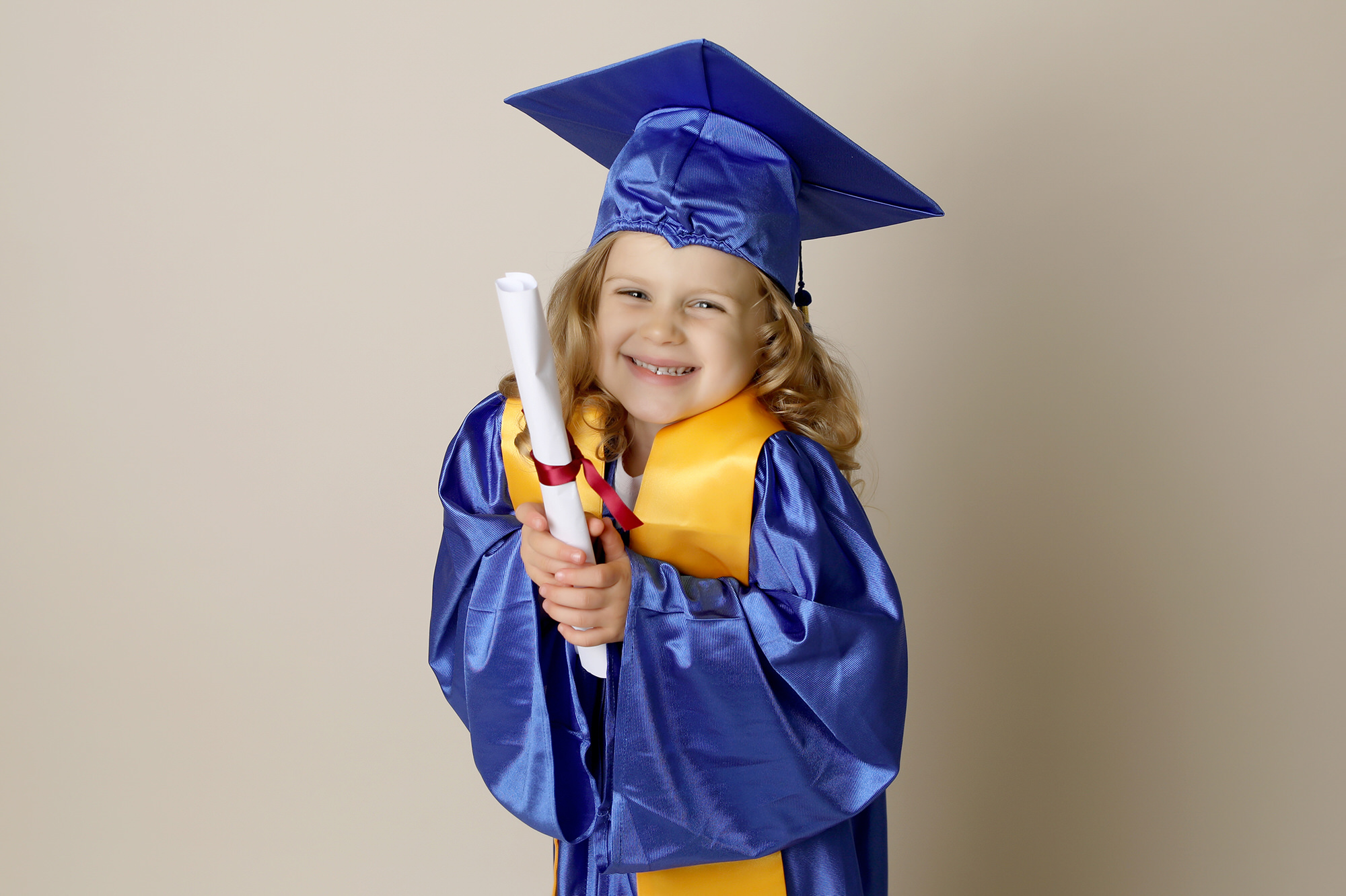 little girl with blonde hair in a blue graduation robe by Nursery Photography in Durham