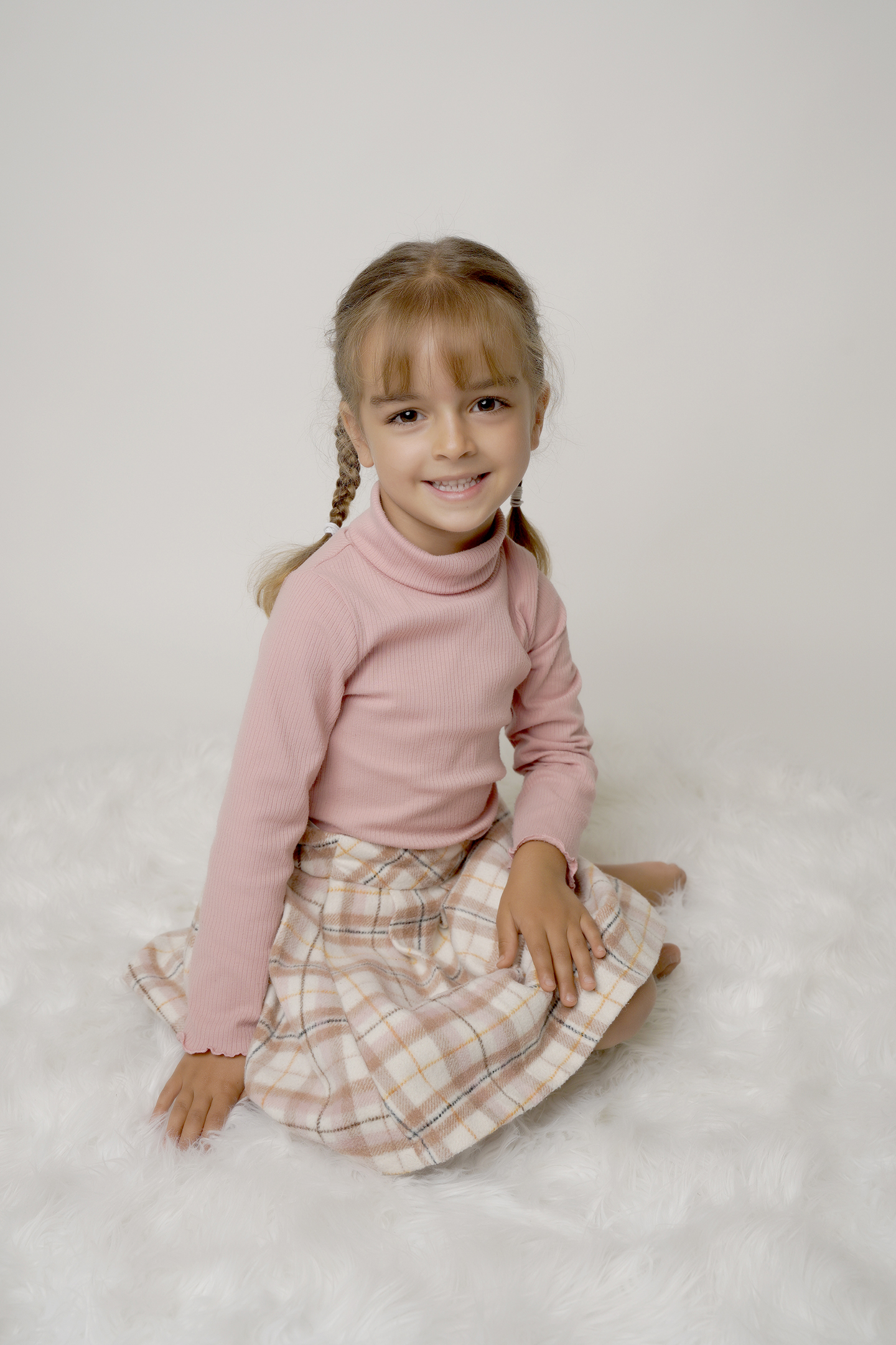 girl with blonde hair in plaits wearing a pink jumper by Nursery Photography in county Durham, Gateshead and Newcastle