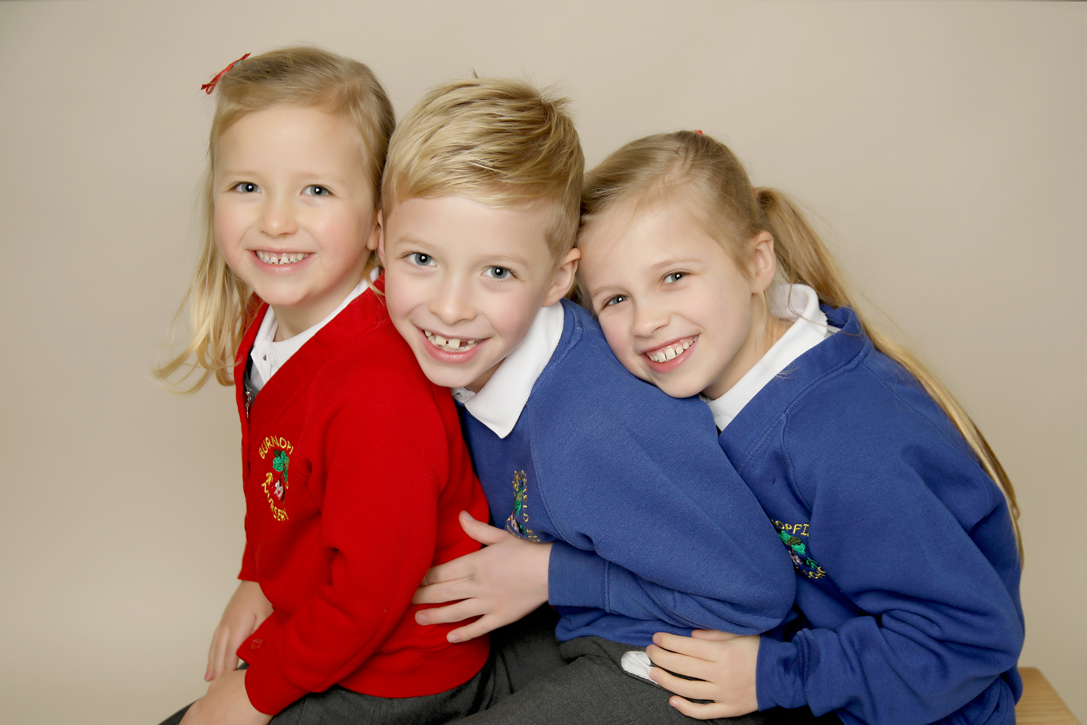 Brother and two sisters in school uniform hugging each other by Primary School Photographer Gateshead, Newcastle and County Durham